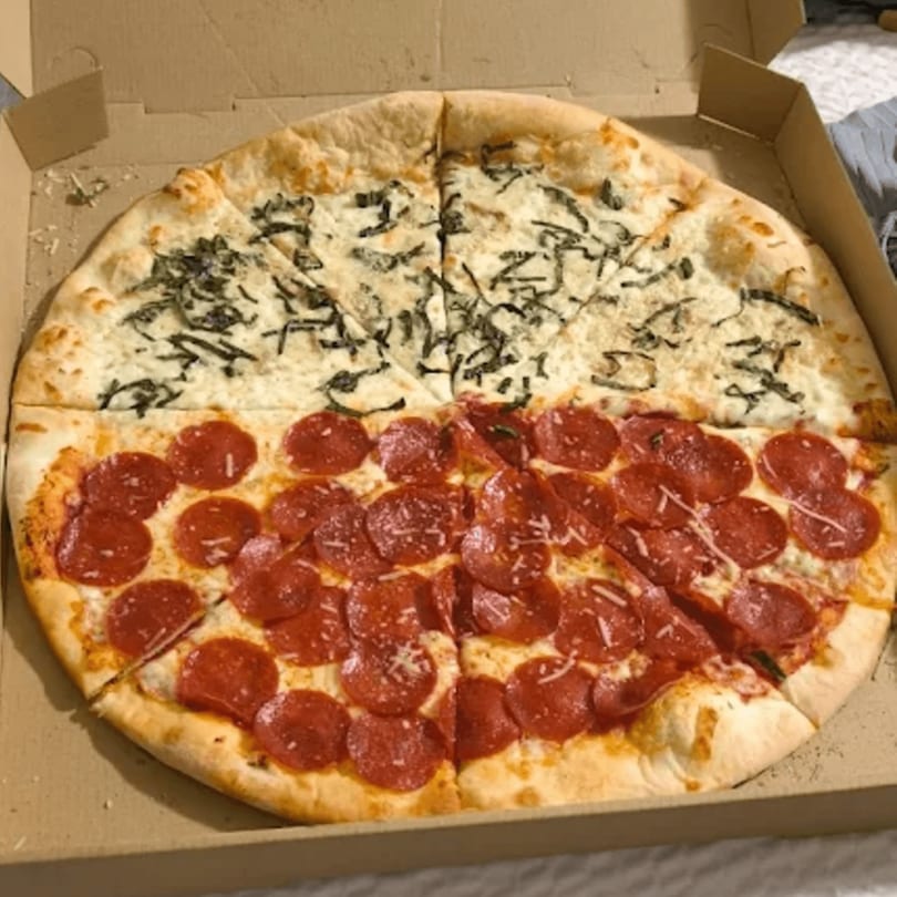 The Pizza Spot's half pepperoni, half white pizza with spinach in a cardboard box.