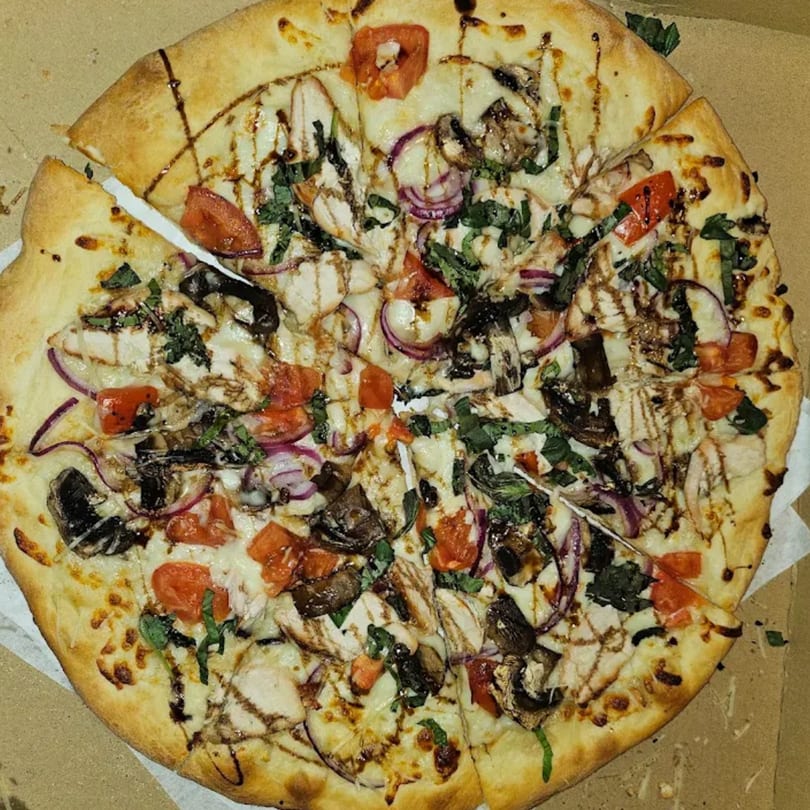 The Pizza Spot's chicken, mushroom, tomato, and red onion pizza with balsamic glaze in a box.